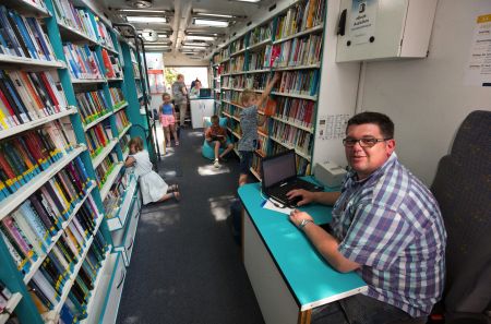 zu sehen ist der Bücherbus und Kinder, die sich Bücher ansehen